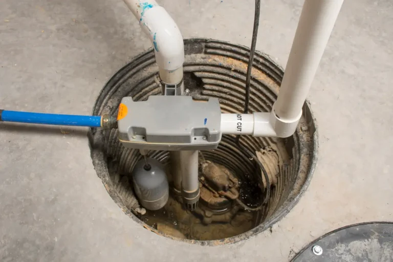 Professional sump pump installation with pump and drainage pipes inside a basement pit for home water protection.