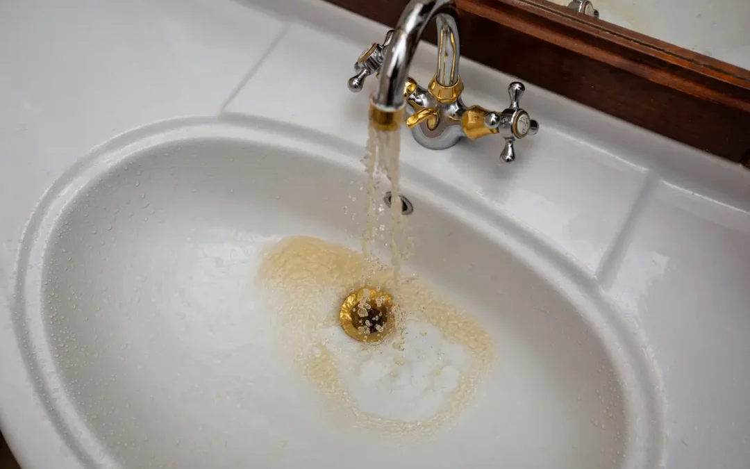 Discolored brown water flowing from a bathroom faucet, showing early signs of plumbing problems homeowners should not ignore.