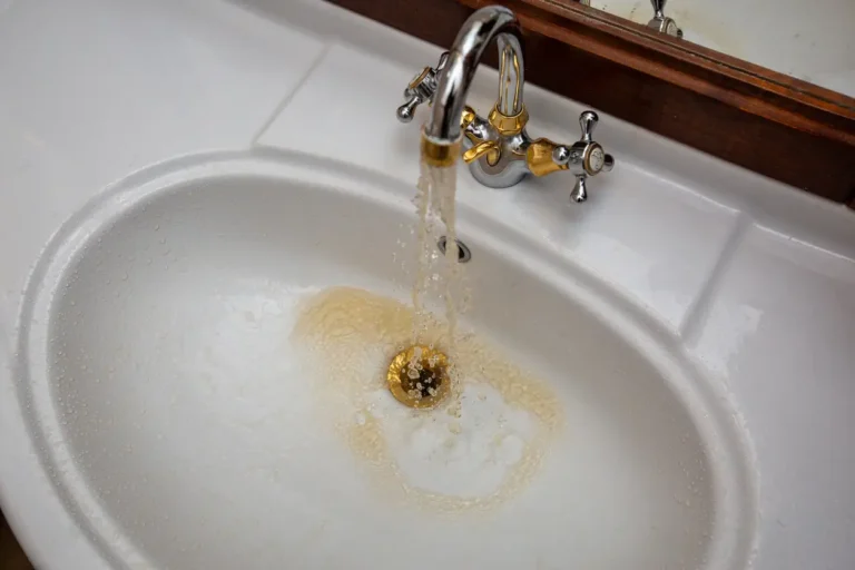 Discolored brown water flowing from a bathroom faucet, showing early signs of plumbing problems homeowners should not ignore.