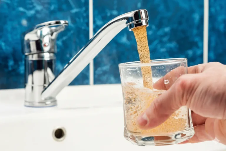 Discolored tap water fills a glass due to backflow contamination in the water supply of a Texas home.